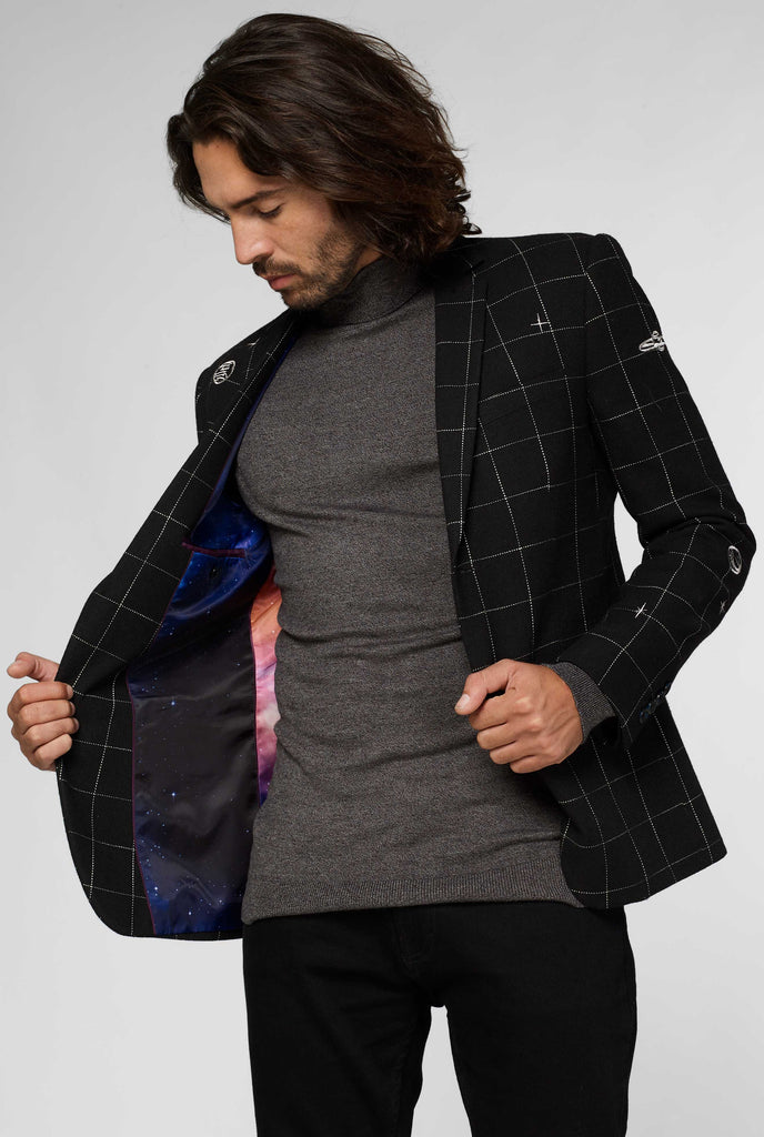 Black jacket with white grid pattern worn by man showing galaxy pattern inside of jacket