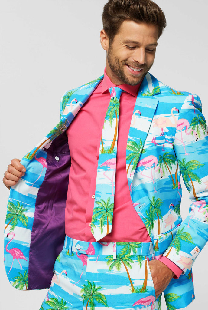 Blue and white suit with tropical flamingo print Flaminguy worn by man inside jacket holding it