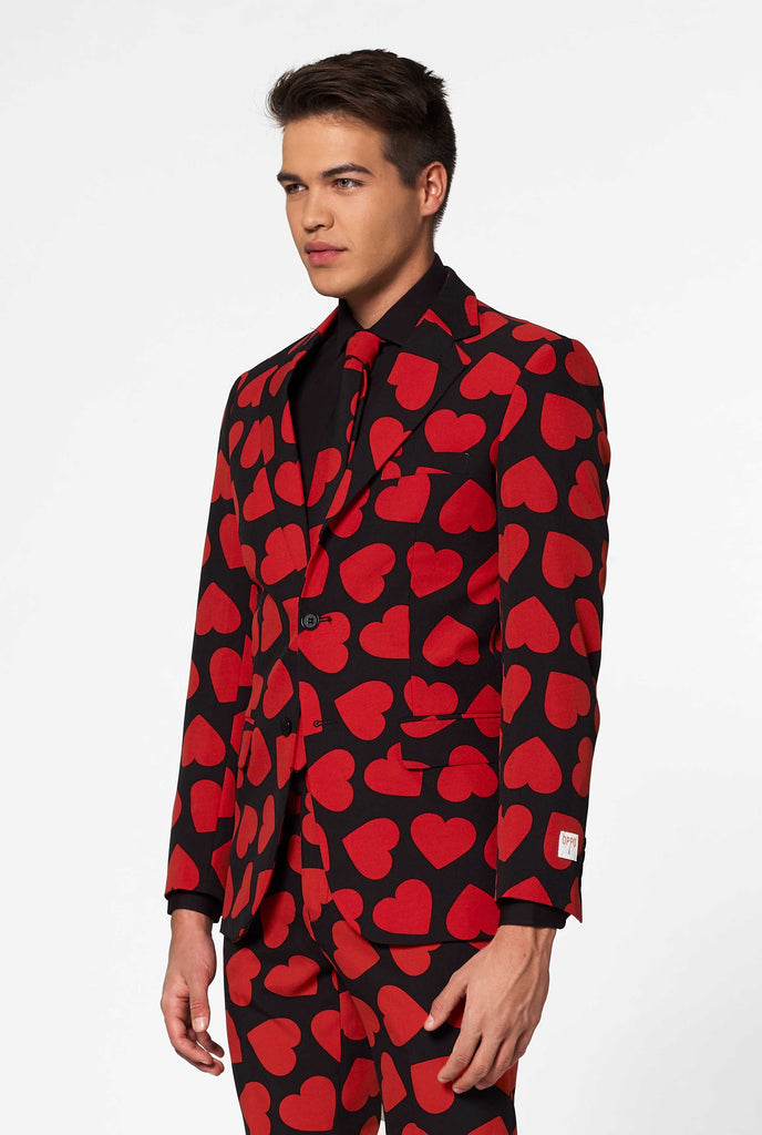 Man wearing black suit with red hearts print