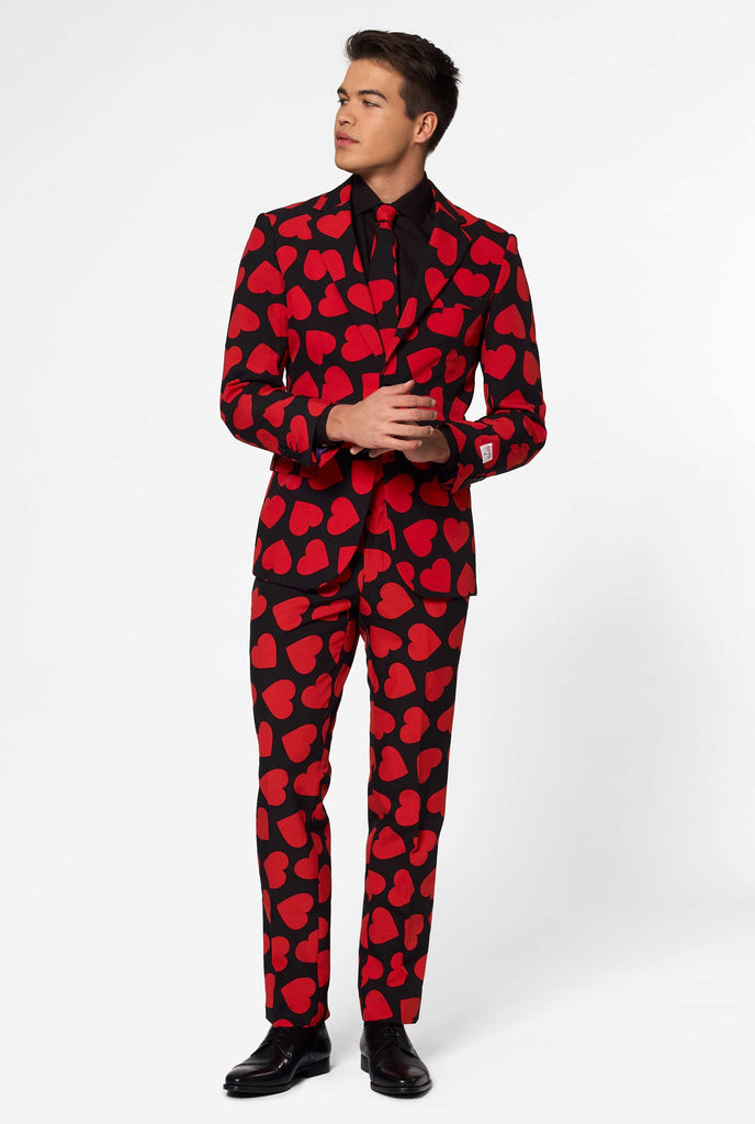 Man wearing black suit with red hearts print