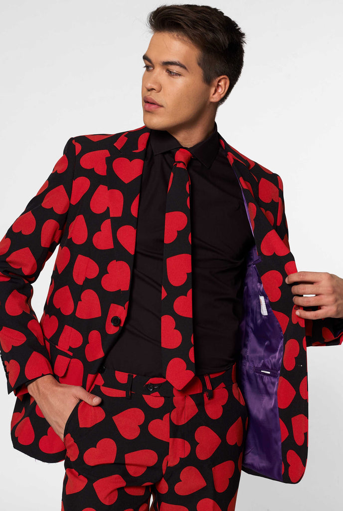 Man wearing black suit with red hearts print