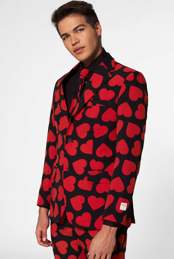 Man wearing black suit with red hearts print