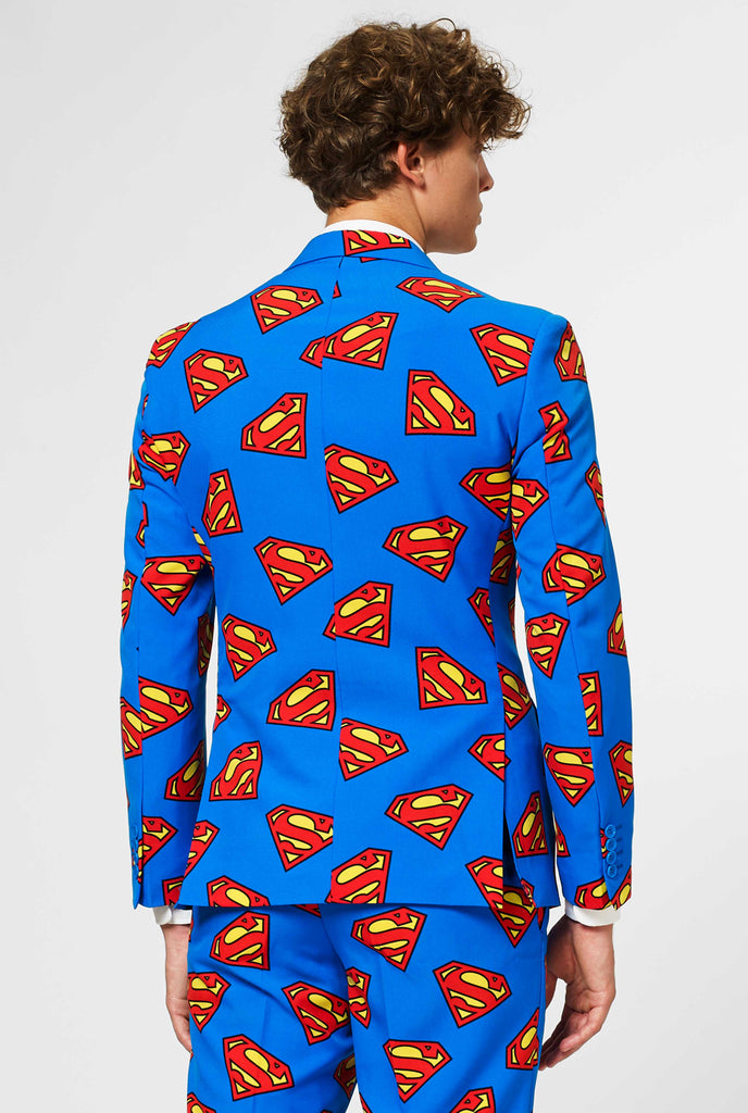 Man wearing blue men's suit with Superman logo print, view from the back