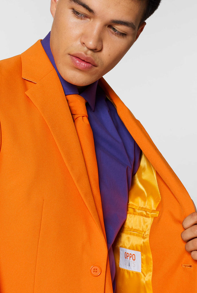 Man wearing orange men's suit with purple dress shirt, close up