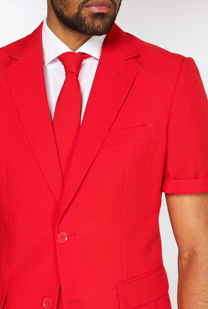 Man wearing red summer suit, consisting of shorts, jacket and tie, close up