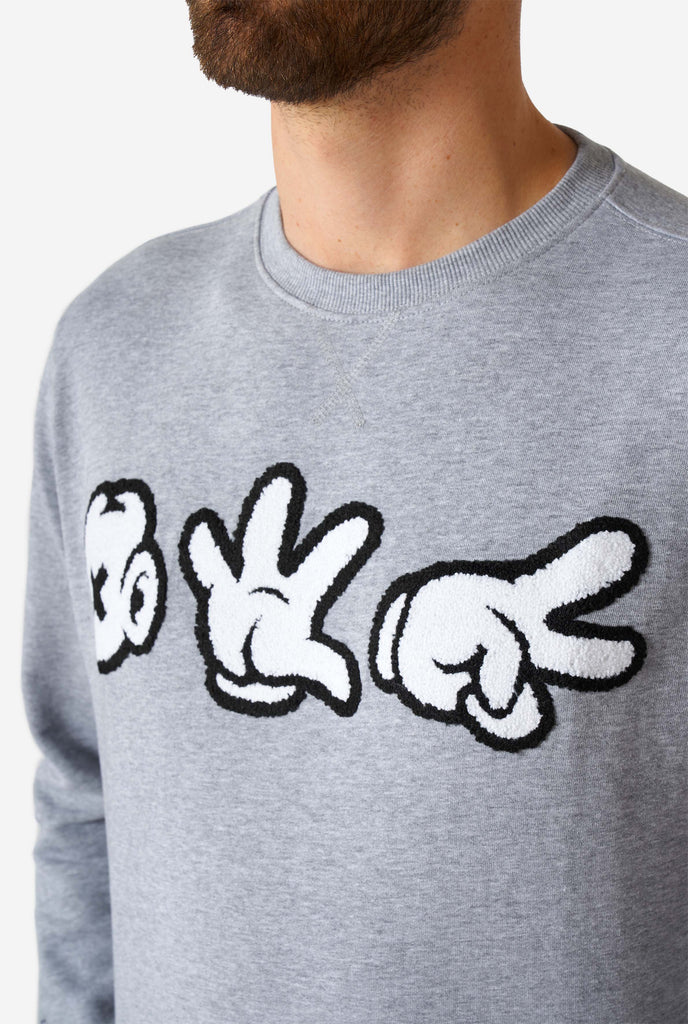 Man wearing grey sweater with chenille rock, paper, scissors embroidery, close up