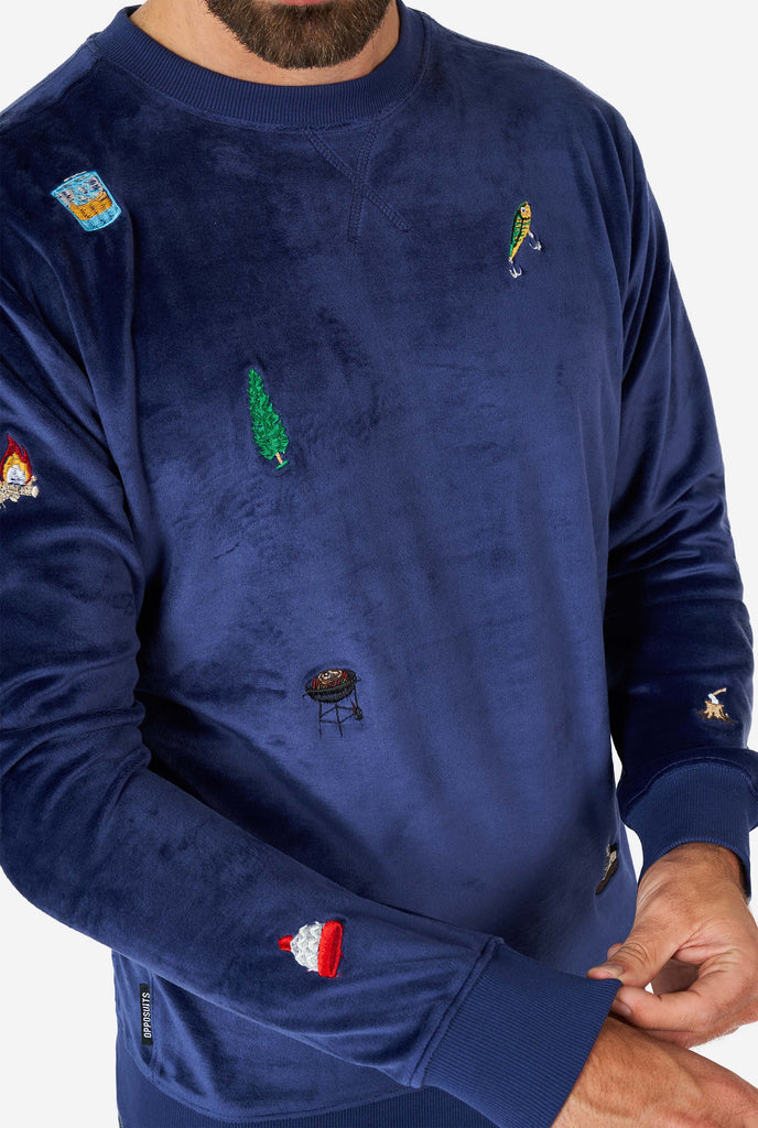 Man wearing velvet blue Christmas sweater with Christmas icons, close up