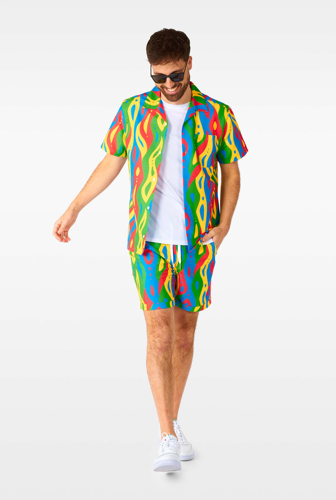 Man wearing colorful summer set, consisting of shirt and shorts.