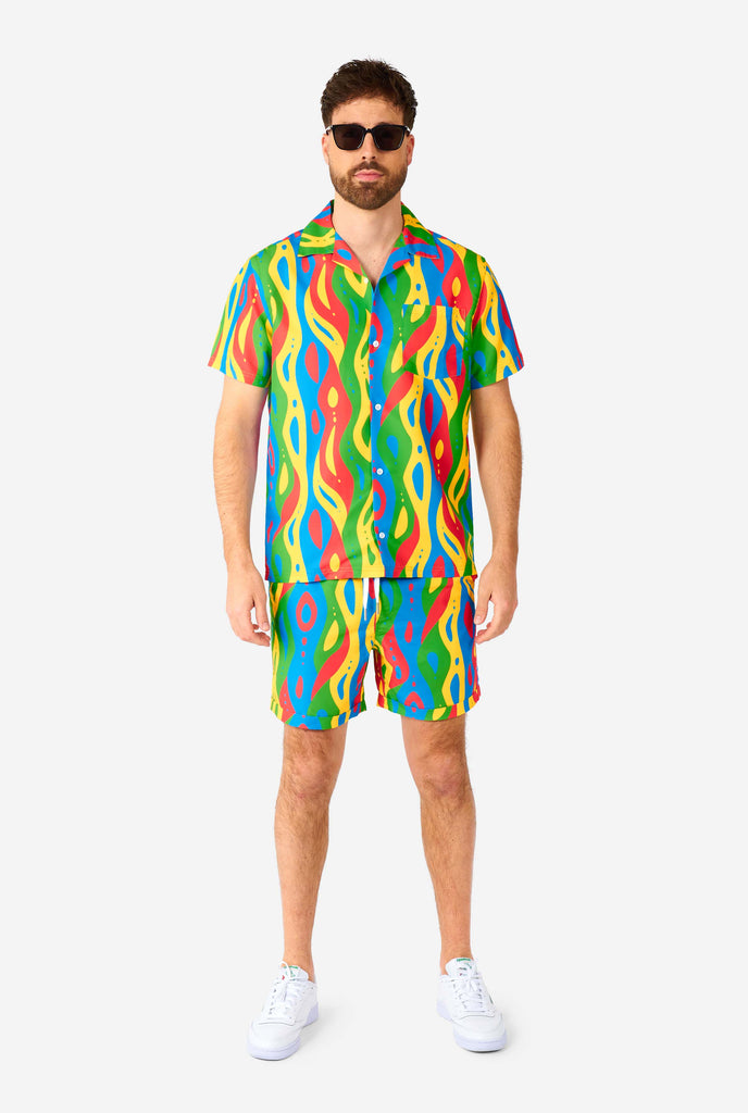 Man wearing colorful summer set, consisting of shirt and shorts.