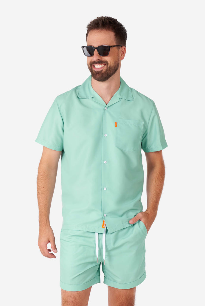 Man wearing green summer set, consisting of short sleeve shirt and shorts.