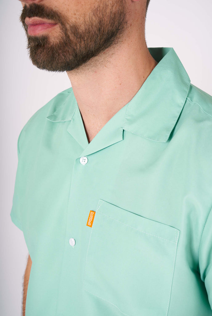 Man wearing green summer set, consisting of short sleeve shirt and shorts. Close up.