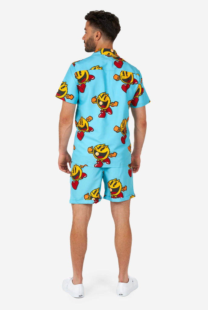 Man wearing blue summer shorts and shirt, with Pac-Man print, view from the back