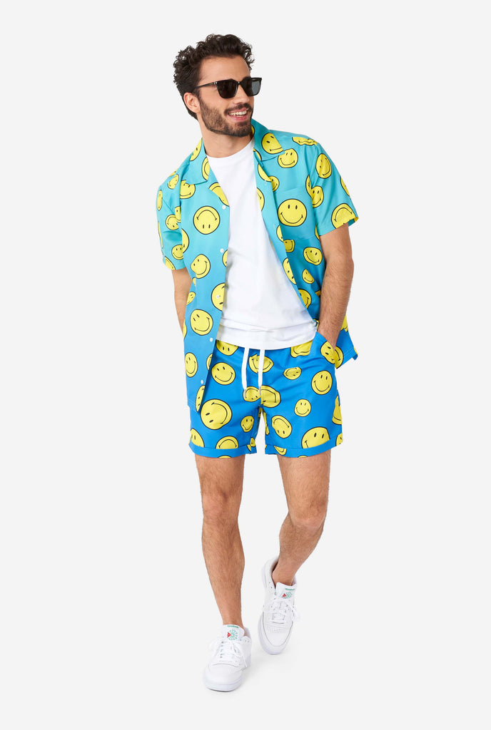 Man wearing blue summer set, consisting of shorts and shirt, with Smiley print