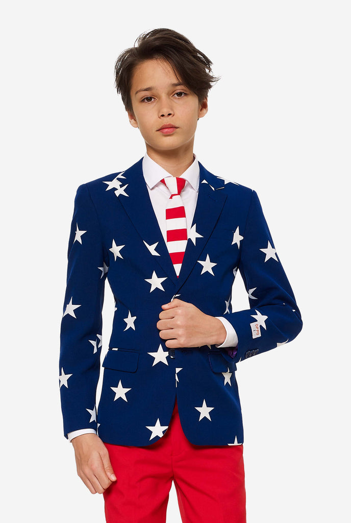 Teen wearing formal USA themed fourth of July suit, consisting of blue jacket and red pants. 