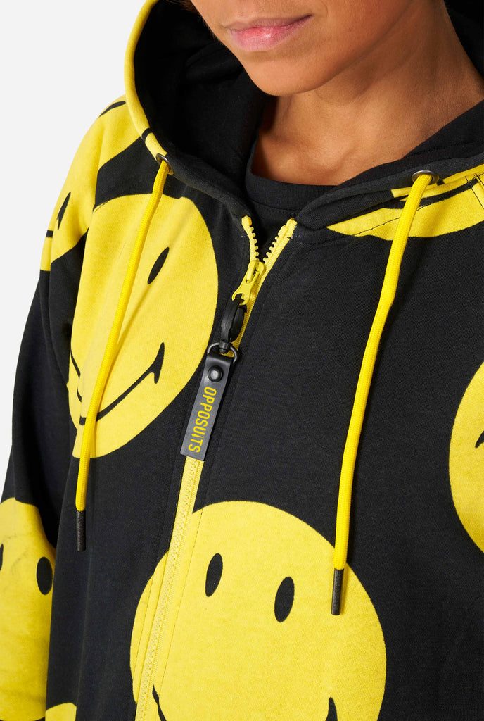 Woman wearing black onesie with yellow smiley print, chest close up